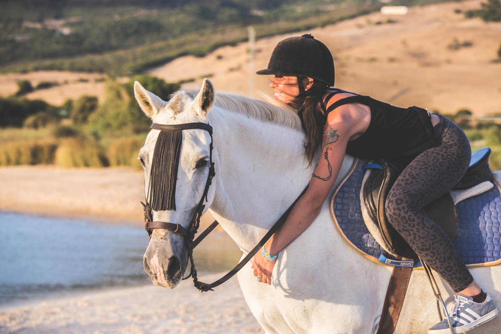 Jinete abrazada al caballo observando el atardecer